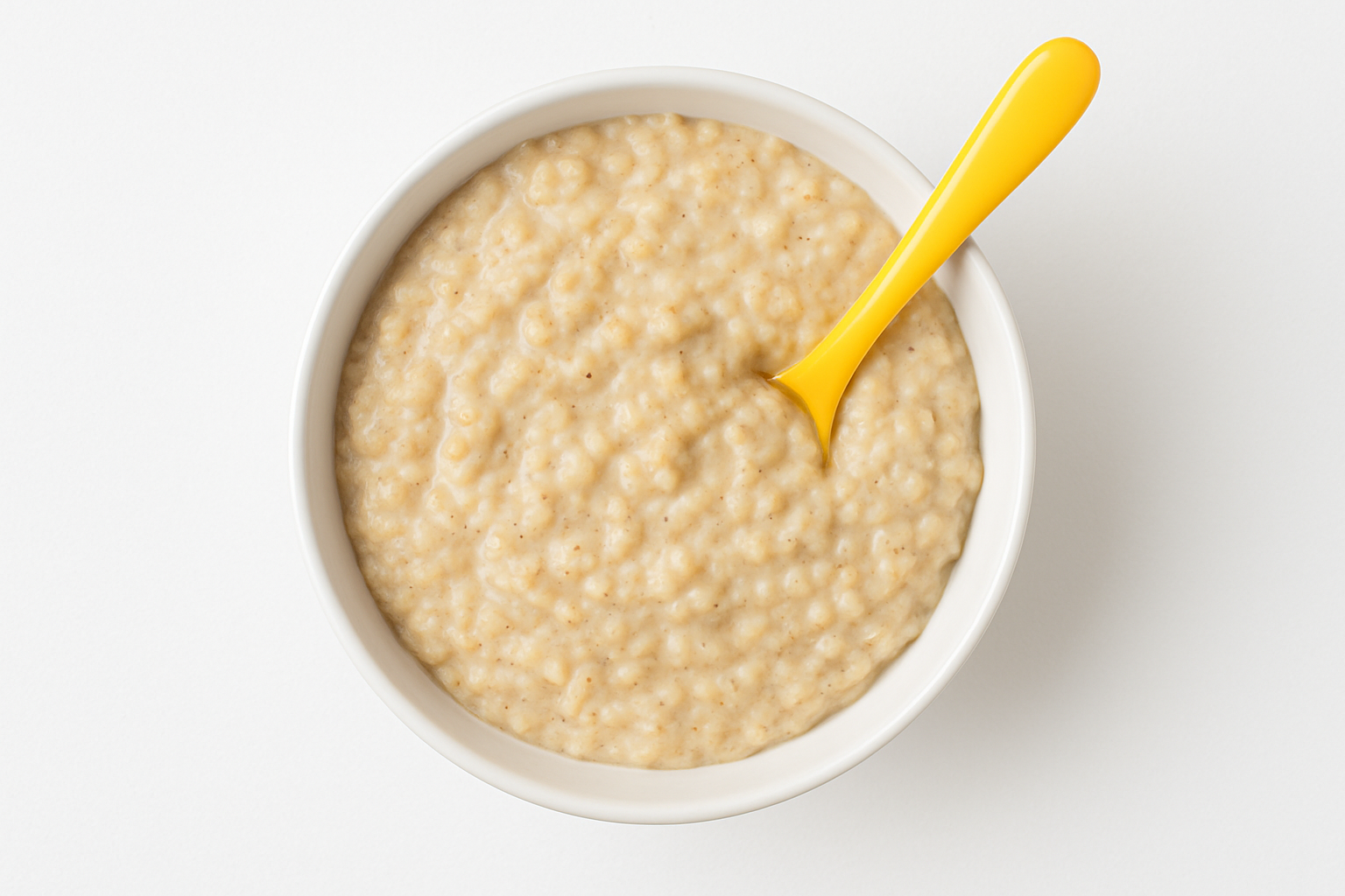 White bowl with yellow spoon with oatmeal inside the bowl and a photo from above